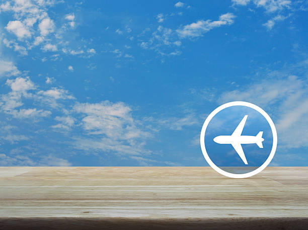 Airplane flat icon on wooden table over blue sky with white clouds, Business transportation service concept