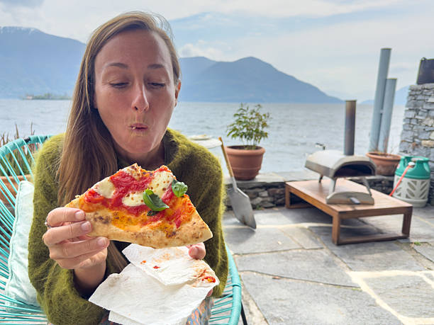 istock Woman Enjoying Pizza by Scenic Lake View 2209893348