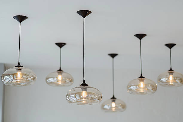 istock Six pendant lights with glass shades hang from a white ceiling. 2209895290