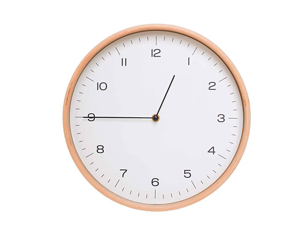 Round wall clock with black frame showing time at 00:45 or 12:45. Ideal for concepts of time or scheduling.