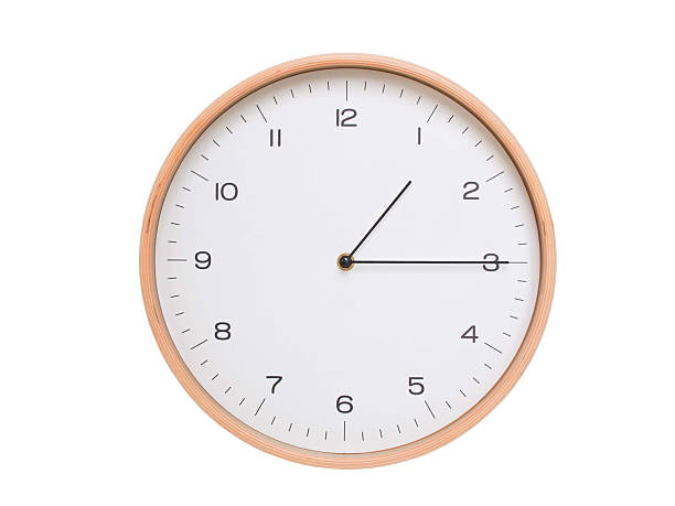 Minimal wall clock with light wood frame and white face displaying 01:15 or 13:15. Perfect for clean, modern concepts about time and scheduling.