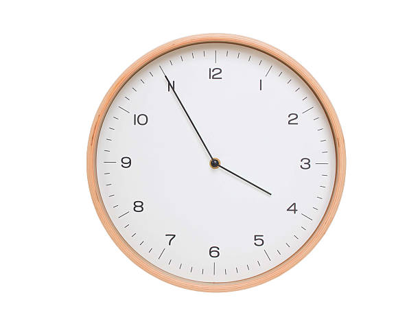 Minimal wall clock with light wood frame and white face displaying 03:55 or 15:55. Perfect for clean, modern concepts about time and scheduling.