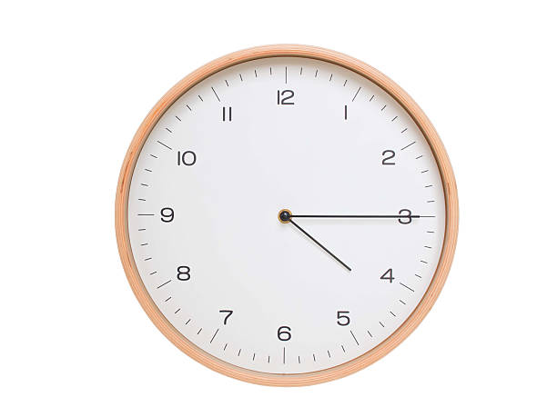 Minimal wall clock with light wood frame and white face displaying 04:15 or 16:15. Perfect for clean, modern concepts about time and scheduling.