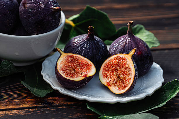 istock Delicate Fresh Ripe Figs With Leaves On White Plate, Rustic Wooden Table. Ficus 2209914973
