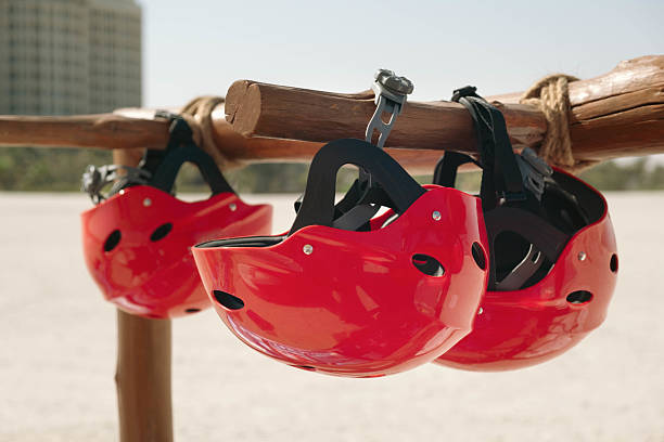 Red protective helmets hang on a wooden mount, ready for use at an outdoor track. Essential for safety during sports or outdoor activities, highlighting their readiness and importance