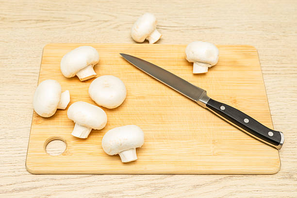champignon mushrooms lie on a wooden cutting board. cooking mushrooms at home. making pureed mushroom soup