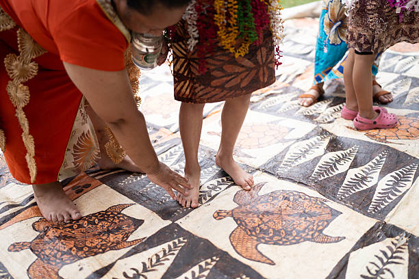 Pacific Islander family, mother and daughters dressed in traditional attire, preparing to perform a traditional dance together in their backyard.