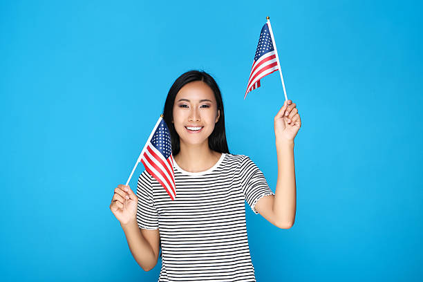 istock Young woman holding American flag on blue background 2209928675