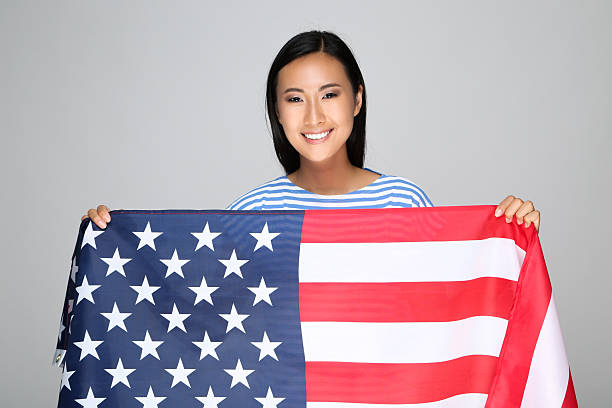 istock Young woman holding American flag on grey background 2209928859