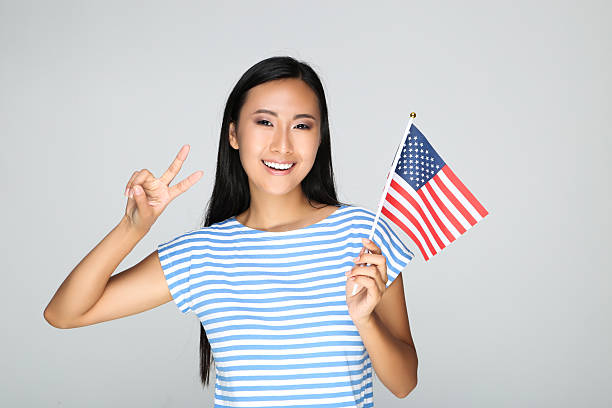 istock Young woman holding American flag on grey background 2209928887