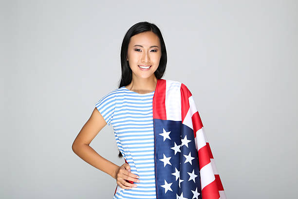 istock Young woman holding American flag on grey background 2209929148