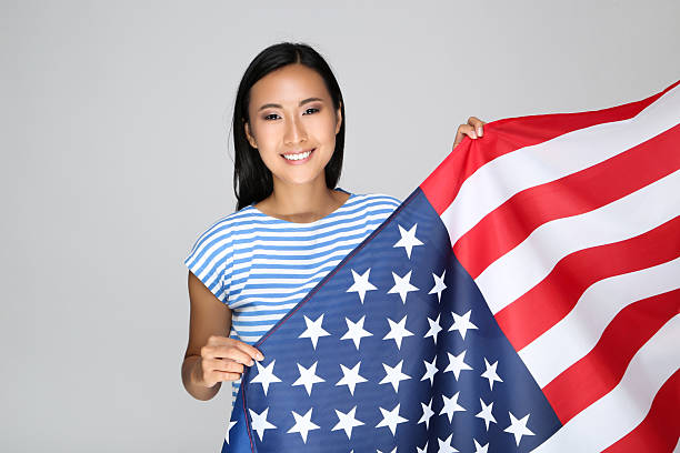 istock Young woman holding American flag on grey background 2209930280