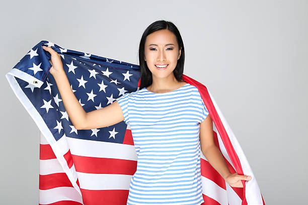 istock Young woman holding American flag on grey background 2209931716
