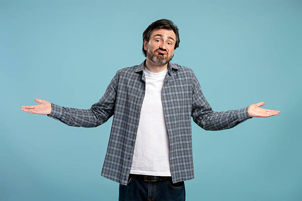 istock Puzzled man shrugging shoulders with open palms on blue background 2209937617