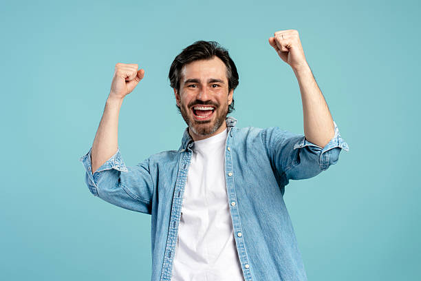 istock Excited confident man celebrating with raised fists on blue background 2209937639