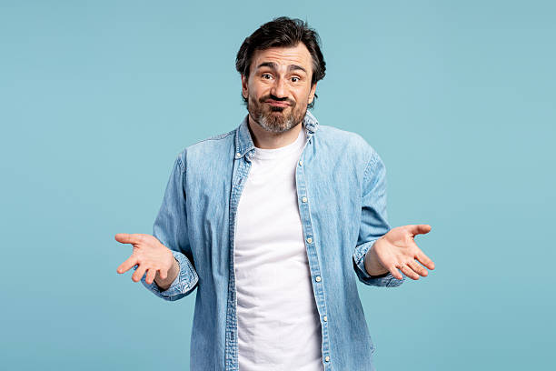 istock Confused man shrugging shoulders gesturing i don't know on blue background 2209937674