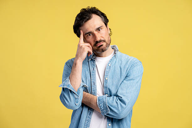 istock Pensive man touching head and reflecting on yellow background 2209941107