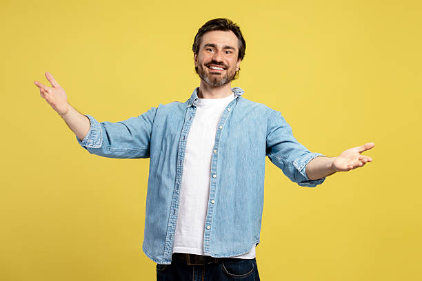 istock Smiling man opening arms and welcoming on yellow background 2209941112