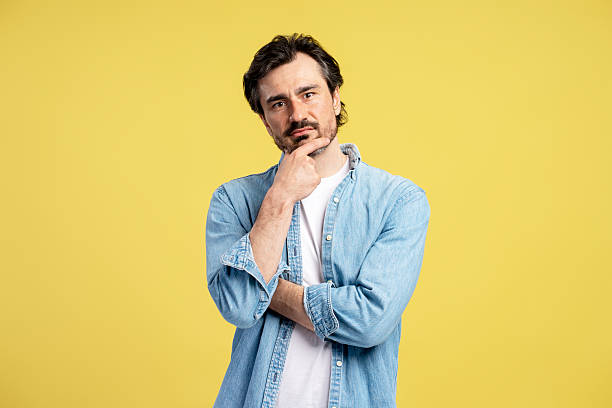 istock Pensive male designer touching chin on yellow background 2209941118