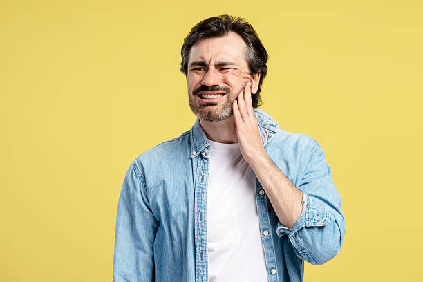 istock Man suffering from toothache touching cheek on yellow background 2209941131