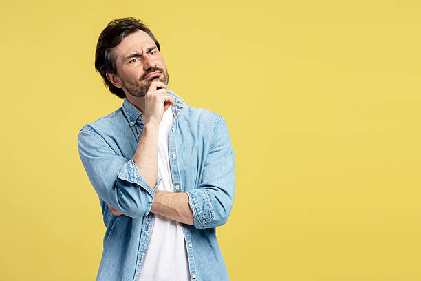 istock Pensive man touching chin and looking away on yellow background 2209941136
