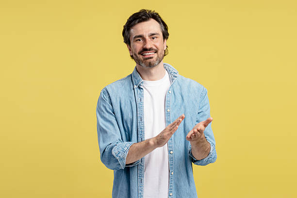istock Enthusiastic man clapping and smiling on yellow background 2209941141