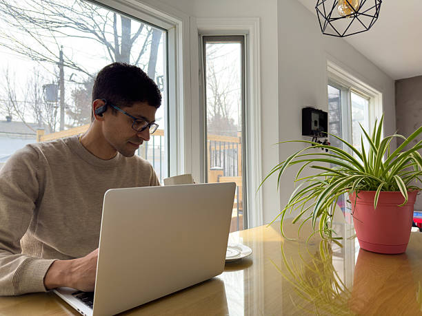 istock Man Working on Laptop at Kitchen Table with Coffee and Plant 2209941616