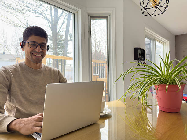 istock Man Working on Laptop at Kitchen Table with Coffee and Plant 2209941627