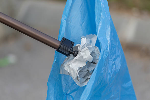 Tourist helping city community to clean streets from garbage. Spiked pole and garbage bag