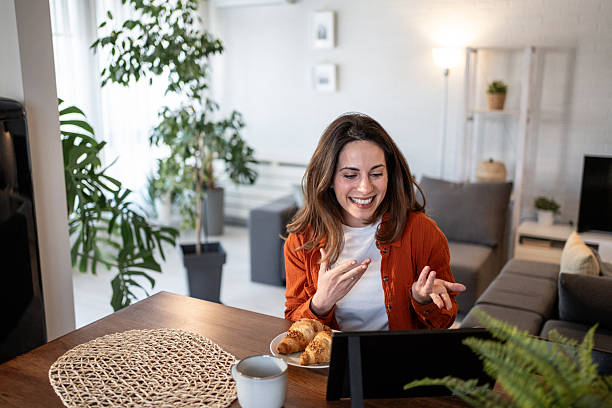 istock Happy woman having a video call while eating breakfast at home 2209947372