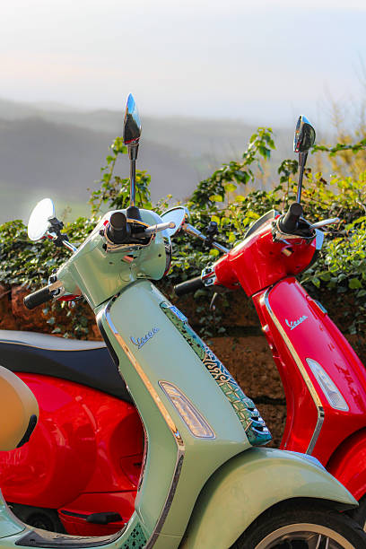 March 2025, Montepulciano - Italy: Two Vespa scooters parked in the medieval mountain town of Montepulciano, located in the province of Siena, in Tuscany. Montepulciano is a famous tourist destination, and Vespa scooters are an international icon for Italy. In the background is quintessential Tuscan landscape, consisting of rolling hills.
