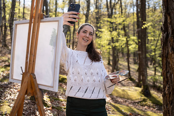 istock Young Artist Taking Selfie in Scenic Forest While Working on Painting 2209951011
