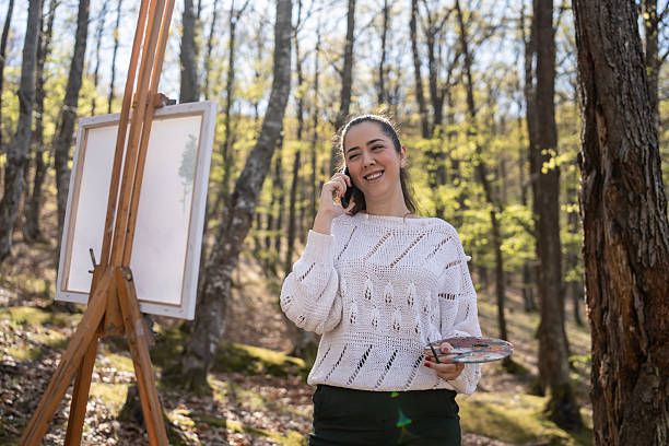 istock Young Artist Painting in Nature While Talking on a Mobile Phone 2209951021