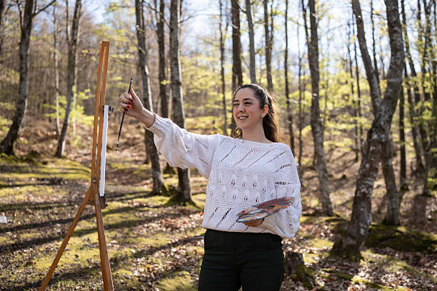 istock Woman Painting Outdoors Surrounded by Nature in a Forest Setting 2209951034
