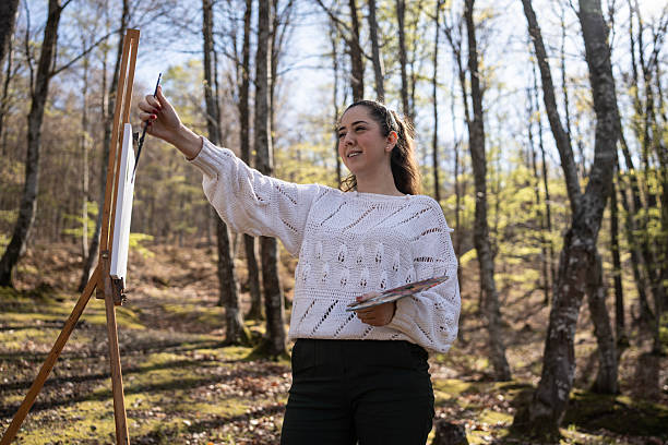 istock Young Woman Painting Outdoors in a Sunny Forest Setting 2209951036