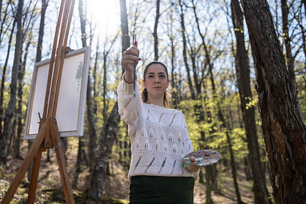 istock Woman Painting Outdoors in a Sunlit Forest Setting 2209951043