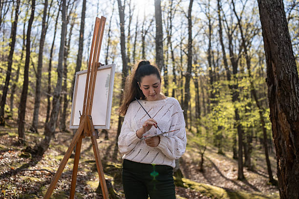 istock Woman Painting Nature on Easel in a Serene Forest Setting 2209951061