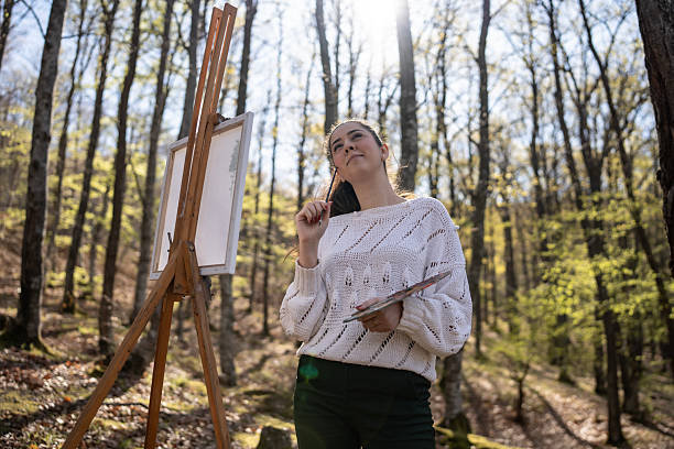 istock Woman Painting Outdoors in Forested Area During Daytime 2209951069