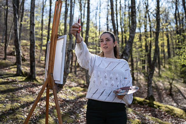 istock Artist Painting Outdoors in a Serene Forest During Sunny Springtime 2209951071