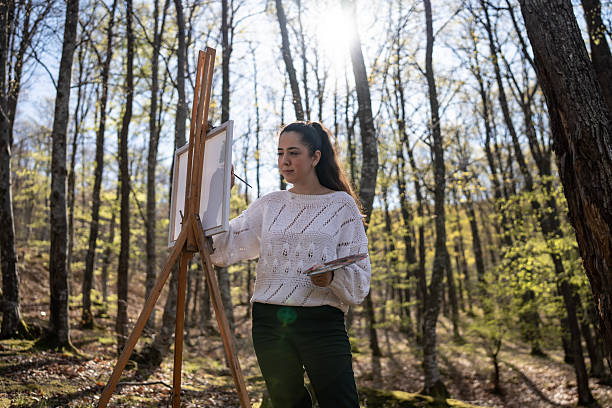 istock Woman Painting Outdoors in Sunlit Forest During a Spring Day 2209951079