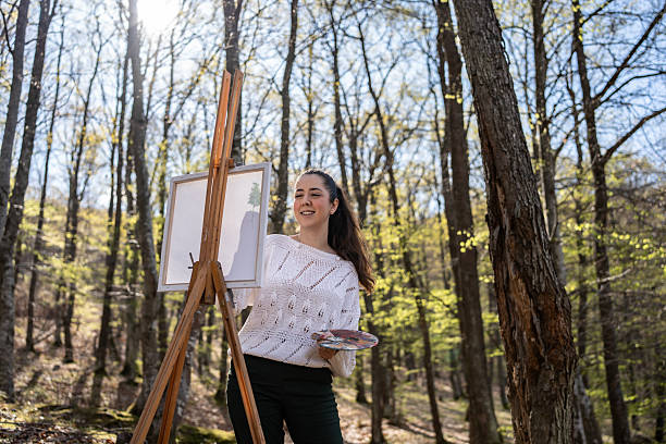 istock Artist Painting on a Canvas Outdoors in a Sunny Forest Setting 2209951093