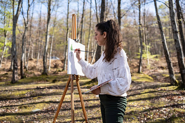 istock Young Woman Painting on Canvas in a Scenic Forest Setting 2209951105