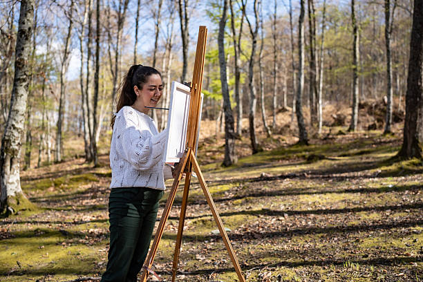 istock Woman Painting Outdoors in a Serene Forest Setting During a Sunny Day 2209951113