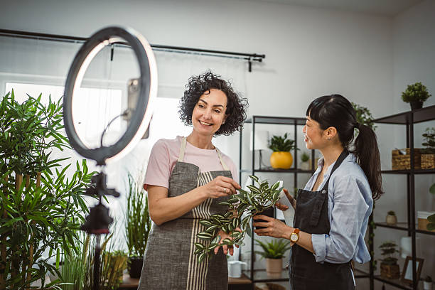 istock Two multicultural woman use cellphone for live stream about home plant 2209953092