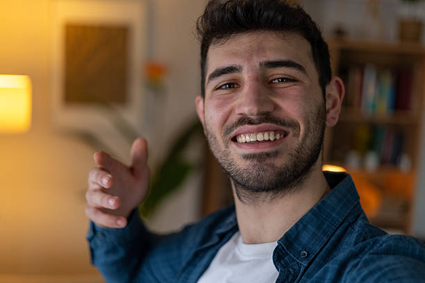 istock Young man making a video call and waving to someone 2209961120