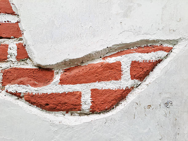 istock Broken plaster with texture of ancient brick wall. A weathered brick wall partially covered by peeling white plaster, revealing the red bricks underneath. 2209966763