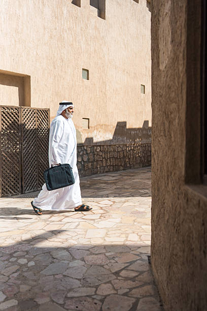 istock Senior Emirati Man Walking Through Stone Courtyard of Traditional Middle Eastern Architecture 2209969704