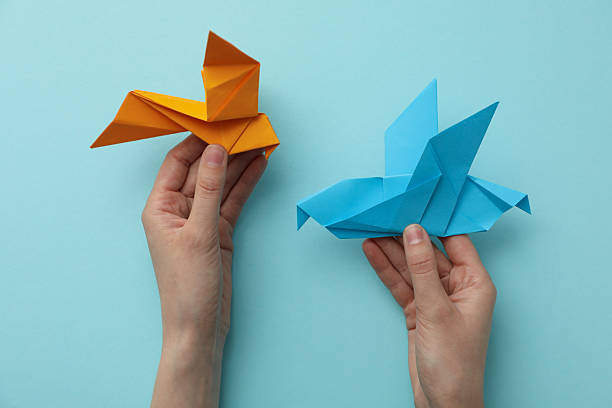 istock Decorative paper birds in hands on blue background, top viewf 2209975407