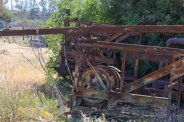istock Rusty machinery stands forgotten amidst wild greenery in a sunlit field, showcasing nature's reclamation of an industrial relic 2209976882