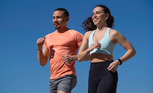 istock Young multiracial smiling couple running outdoors under a clear blue sky, enjoying their active lifestyle and promoting fitness 2209985552